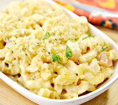 a white bowl filled with macaroni and cheese on top of a wooden table