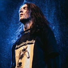 a man with long hair standing in the rain