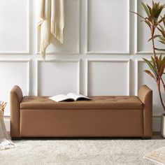 an open book sitting on top of a brown bench next to a potted plant