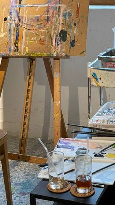 an artist's easel with paint and glasses on it