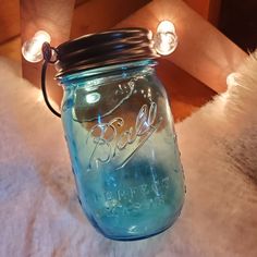 a blue mason jar sitting on top of a white fur covered floor next to lights