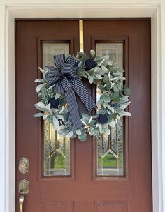 a wreath on the front door of a house with blue and white ribbons hanging from it