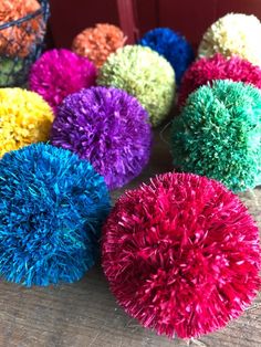 multi colored pom poms sitting on top of a wooden table