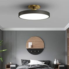 a bedroom with grey walls and a round mirror on the wall above the headboard