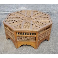 an old wooden table with intricate carvings on the top and bottom, sitting on concrete