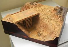 a model of a wooden structure on top of a dryer with rocks and dirt