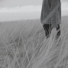 a person standing in tall grass with their back to the camera