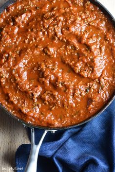 a skillet filled with sauce on top of a blue cloth