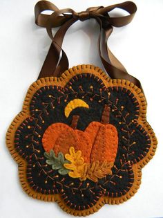 an orange and black pumpkin hanging from a brown ribbon