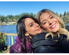 two women taking a selfie in front of a lake