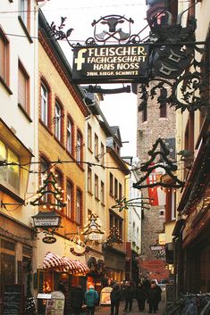 people are walking down an alley way with shops and stores on both sides that have christmas lights strung from the ceiling