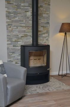 a living room with a chair and a fire place in the corner, next to a lamp