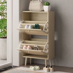 a wooden shoe rack with shoes and purses on it next to a potted plant