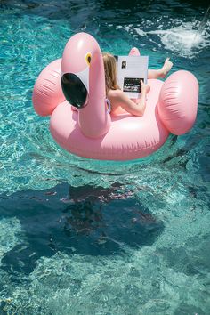 a woman sitting on an inflatable flamingo reading a book with the caption here's to you, weekend