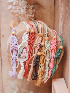 a bunch of bracelets are hanging on a wooden board with tassels around them