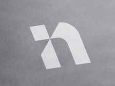 the letter n is made up of white paper on a gray surface with a black and white logo