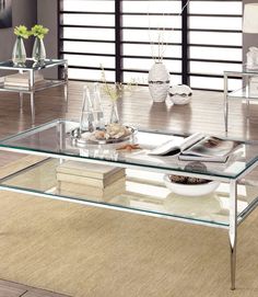 a glass coffee table sitting on top of a wooden floor next to a vase filled with flowers