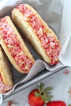 three strawberry shortbreads sitting in a basket next to some strawberries