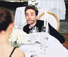 a man sitting at a table with flowers in his mouth