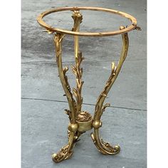 an ornately decorated gold metal table with glass top on the sidewalk in front of a building