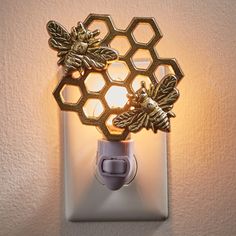 a light that is on the side of a wall with a bee and honeycomb