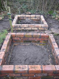 an empty brick garden bed is shown in the middle of some dirt and grass area