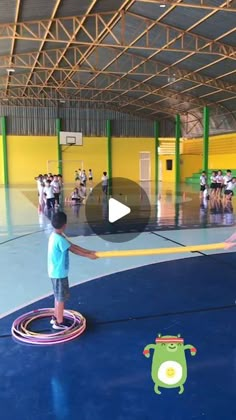 a young boy is playing with a hula hoop in an indoor gym while others watch