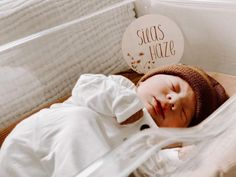 a baby sleeping in a crib with a sign that says suas haze