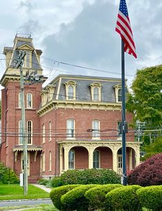 an american flag flying in front of a red brick building