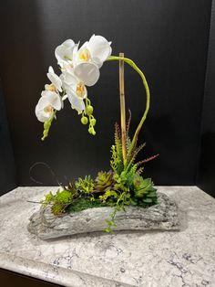 an arrangement of white flowers and greenery on a marble slab