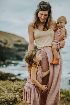 a woman and two children standing by the ocean