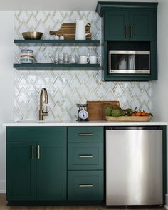 a kitchen with green cabinets and stainless steel appliances