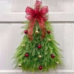 a christmas tree made out of green leaves and red balls on the front door handle