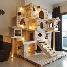 a cat house made out of wooden pallets with lights on the windowsills