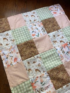 a close up of a patchwork quilt on a wooden floor with flowers and deers