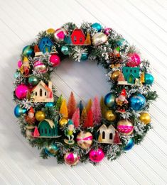 a christmas wreath hanging on the wall with ornaments and decorations around it's edges