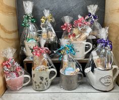 several mugs filled with candy and wrapped in cellophane, sitting on a shelf