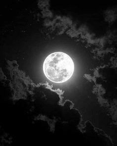 the full moon is shining brightly in the dark night sky with fluffy clouds around it