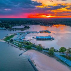 an aerial view of a marina at sunset with the sun setting over the water and clouds in the sky