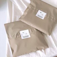 two brown envelopes sitting on top of a white sheet covered bed next to each other