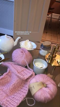 knitting supplies are sitting on a table next to a tea pot