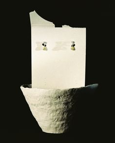 a pair of earrings sitting on top of a piece of paper in front of a black background