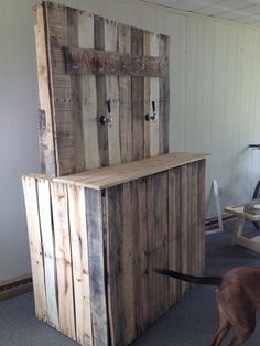 a dog is standing in front of a wooden box with doors on it's sides