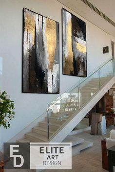 two paintings are hanging on the wall next to a stair case in a living room