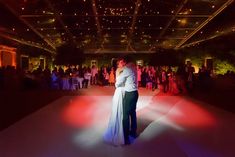 a bride and groom dance on the dance floor at their wedding reception in front of an audience