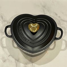 a heart - shaped casserole sits on a marble countertop with the word love spelled in gold