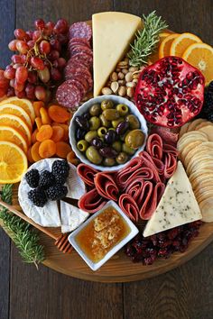 a platter filled with cheese, crackers, olives, fruit and nuts