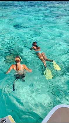 two people are swimming in the clear blue water