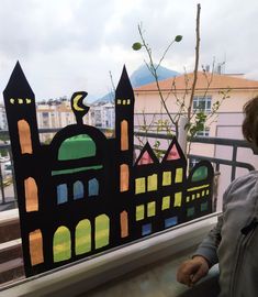 a person standing in front of a window with paper cut out of buildings on it