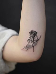 a small rose tattoo on the left side of the right arm, with an arrow in it